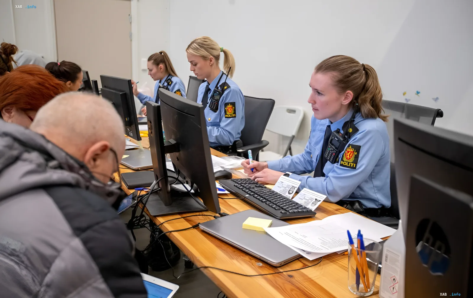 Norwegian police officers at workstations with documents and computers, illustrating administrative procedures related to the case of discrimination against a Russian scientist in Norway.