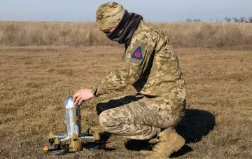Украинский военнослужащий в камуфляже проверяет дрон-камикадзе перед запуском в поле, символизируя подготовку к перехвату вражеских БПЛА