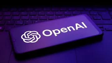 Логотип OpenAI на экране смартфона на фоне клавиатуры ноутбука в фиолетовом освещении, символизирующий закрытие команды Preparedness и оценку рисков ИИ
