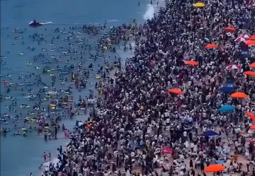 Переполненный пляж Дамейша в Шэньчжэне: толпы туристов на берегу и в воде, яркие зонты, наглядный пример «моря людей»