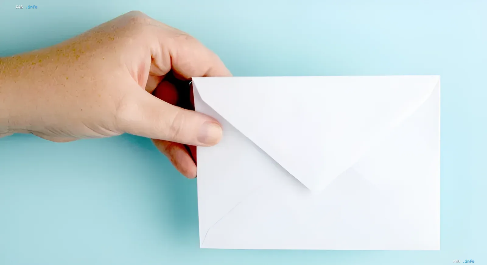 Hand hält einen weißen Umschlag auf blauem Hintergrund – Symbol für den Übergang zu kyrillischen E-Mail-Adressen in Russland