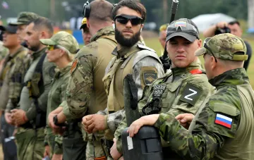 Російські військові в камуфляжі з ідентифікаційними знаками 'Z' та прапором РФ на фоні польових умов — ілюстрація до даних ГУР про втрати, що перевищують набір контрактників