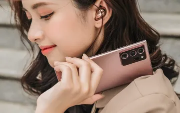 Женщина держит розовый Samsung Galaxy S26 FE, демонстрируя камеру и дизайн устройства в контексте обзора характеристик из Google Play Console