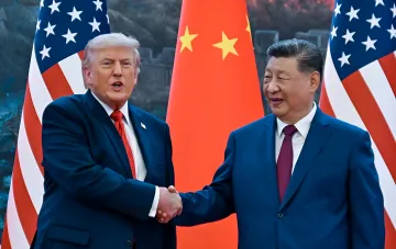 Дональд Трамп и Си Цзиньпин пожимают руки на фоне флагов США и Китая, иллюстрируя сокращенный визит председателя КНР в США и пропуск Генассамблеи ООН