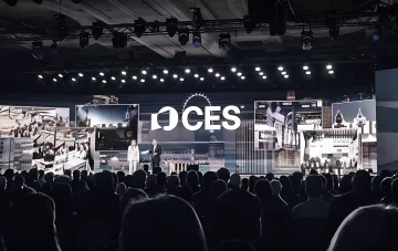 Спикеры на сцене выставки CES с логотипом на фоне, демонстрируя масштаб мероприятия, куда отправляются украинские студенты