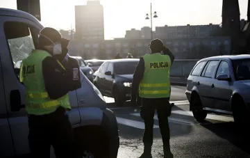 Польские полицейские в жилетах POLICJA останавливают автомобили на дороге, иллюстрируя строгий контроль и депортацию за агрессию против правоохранителей