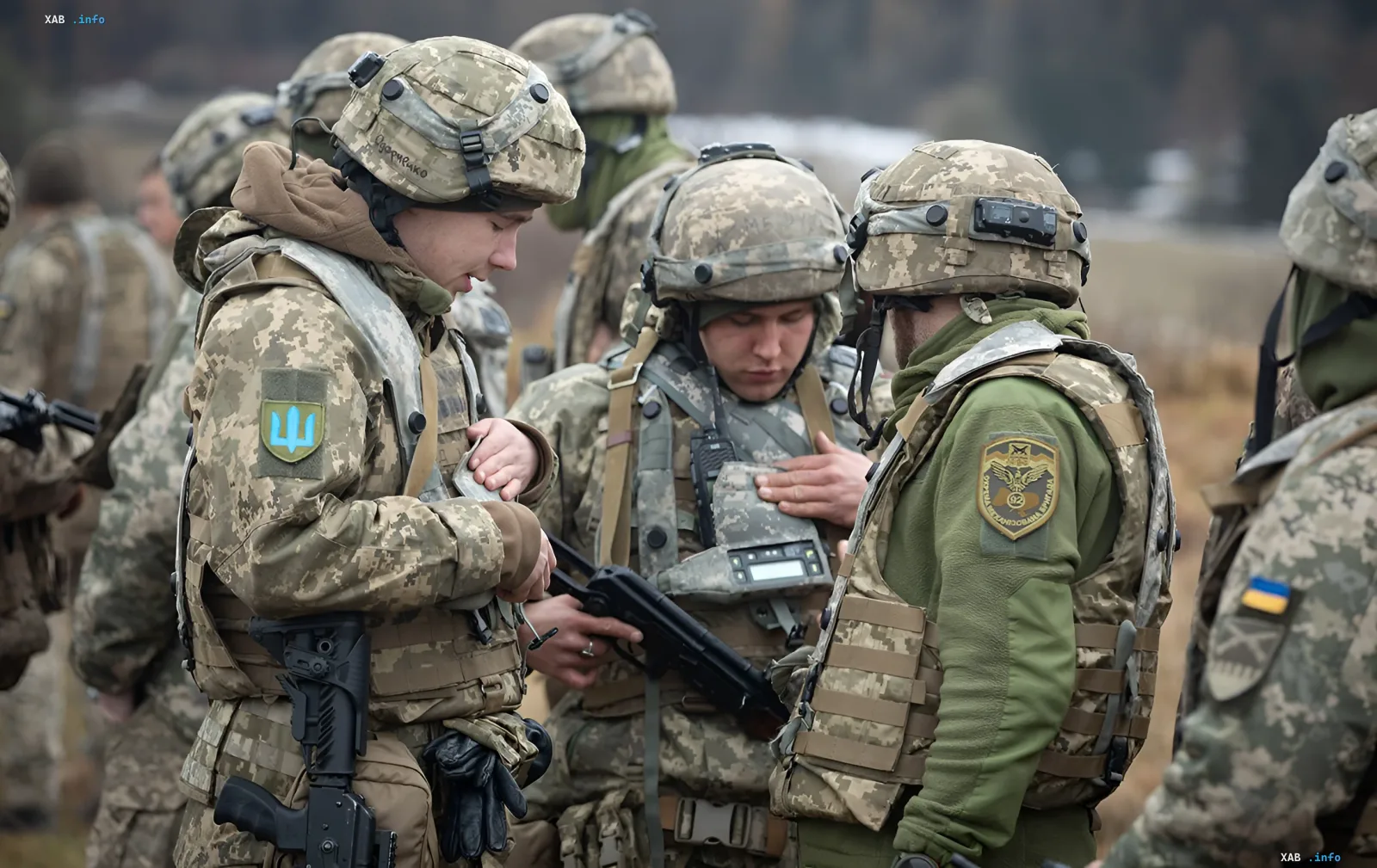 Украинские военные в камуфляжной форме обсуждают тактику, один из них держит оружие, на рукавах видны эмблемы Вооруженных сил Украины