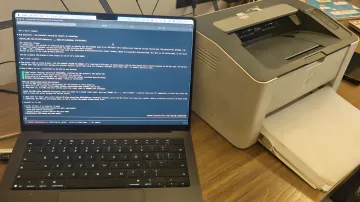 MacBook laptop with open terminal where AI Claude helps configure driver for legacy HP Laser 1008a printer on macOS