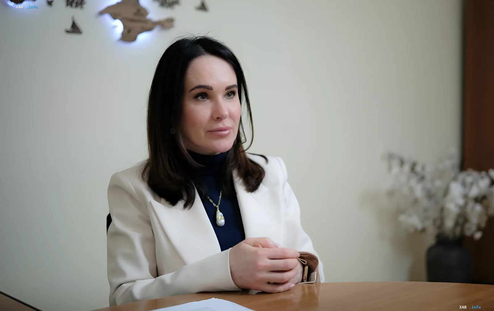 Irina Mudraya in weißem Blazer und marineblauem Rollkragenpullover, sitzt an einem Tisch während einer offiziellen Veranstaltung oder eines Interviews, erhielt Verdacht von NABU im Rahmen der Operation „Forrest Gump“