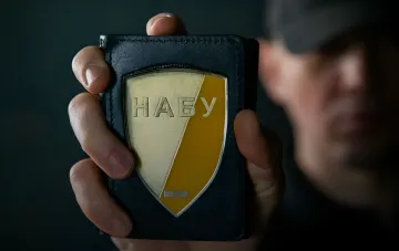 Ein NAABU-Beamter zeigt sein Dienstausweis mit dem NAABU-Emblem während der Operation 'Forrest Gump', die eine Geldwäsche-Schmiede im Wert von 150 Millionen Hrywnja im Zusammenhang mit der Kaution im Fall 'Midas' aufdeckt
