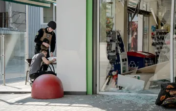 Polizist und Geschäftsinhaber dokumentieren Explosionsschäden in einem Laden — Beispiel eines Unternehmens, das Anspruch auf Steueramnestie hat