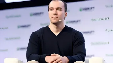 Грег Брокман, соучредитель OpenAI, на конференции с серьезным выражением лица, обсуждая риски ИИ и угрозы IPO