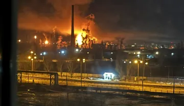 Пожар на промышленном объекте ночью: огненный взрыв у трубы завода, вид с дороги — иллюстрация к фактчеку удара по заводу «Прогресс» в Самаре или Чебоксарах