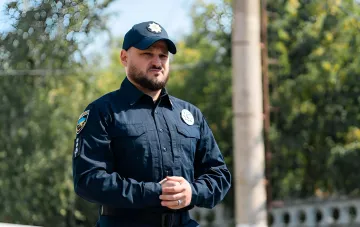 Полицейский в форме на фоне деревьев, символизирующий усиление контроля за дорожным движением в связи с новым законом № 15348