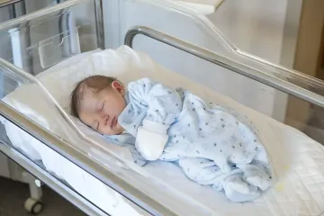Newborn baby in a hospital bassinet illustrating late fatherhood statistics in Uzbekistan