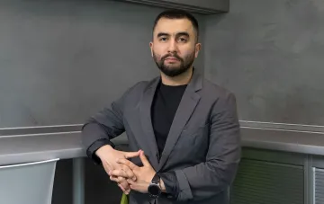 Жумадилов в сером пиджаке на фоне современного интерьера: раскрыл рекордные поставки дронов и утроенный бюджет АОЗ ДОТ на вооружение в 1,7 трлн грн перед отставкой