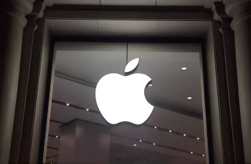 Светящийся логотип Apple на витрине магазина на фоне новости об утечке из беты macOS 26.7, раскрывшей умный дисплей HomePad с циферблатами