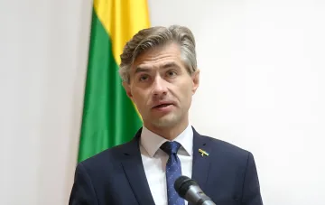 Глава МИД Литвы выступает с заявлением о вступлении Украины в ЕС до 2030 года на фоне литовского флага, на лацкане значок с украинским флагом