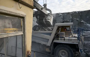 Excavator loading rock into a dump truck at a quarry — illustration of the ecological tax on waste disposal