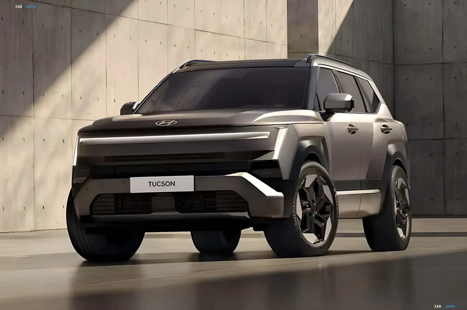 Hyundai Tucson п'ятого покоління у сріблясто-графітовому кольорі: великий SUV із сміливим дизайном та Х-подібною світлотехнікою на тлі бетонної стіни