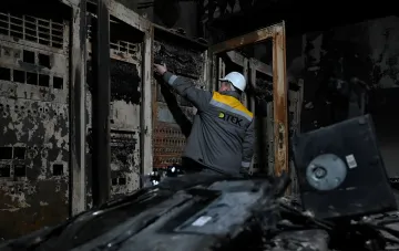 Энергетик DTEK осматривает повреждённое электрооборудование после ночной атаки на Киев