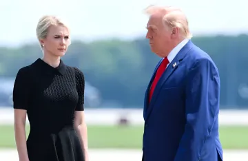 Natalie Harp in einem schwarzen Kleid neben Donald Trump in einem blauen Anzug auf einem Flugfeld – Bild aus der Geschichte über den politischen Skandal in Washington