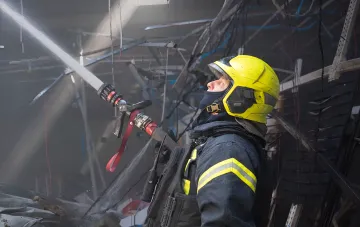 Пожарный ликвидирует возгорание после удара дронов по Одесской области: струя воды направлена на повреждённое здание с обломками и оборванными проводами