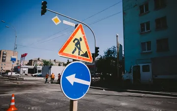 Дорожные знаки о работах и направлении объезда на фоне перекрытого участка в Киеве перед закрытием моста Метро