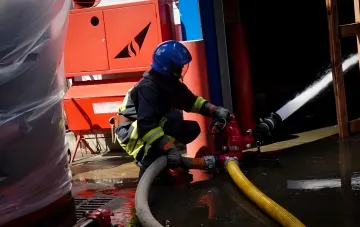 Пожарный работает с гидрантом и направляет струю воды на объект критической инфраструктуры в Киеве после атаки — возможны перебои с горячей водой