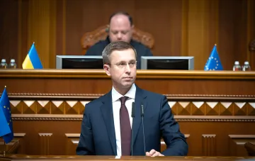 Rede zur Beschleunigung des Verkaufs der Sense Bank und zur Lösung der Probleme mit der NBU: Redner am Podium mit ukrainischer und EU-Flagge
