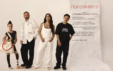 Благотворительный мерч ПУМБ «Поколение 91»: модель в белой рубашке с вышивкой и в чёрной футболке на фоне Акта независимости Украины к 35-летию Независимости