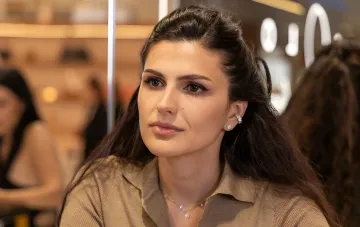 Украинский бренд SOLO for Diamonds: представитель бренда в элегантных бриллиантовых серьгах и ожерелье на фоне выставочного пространства