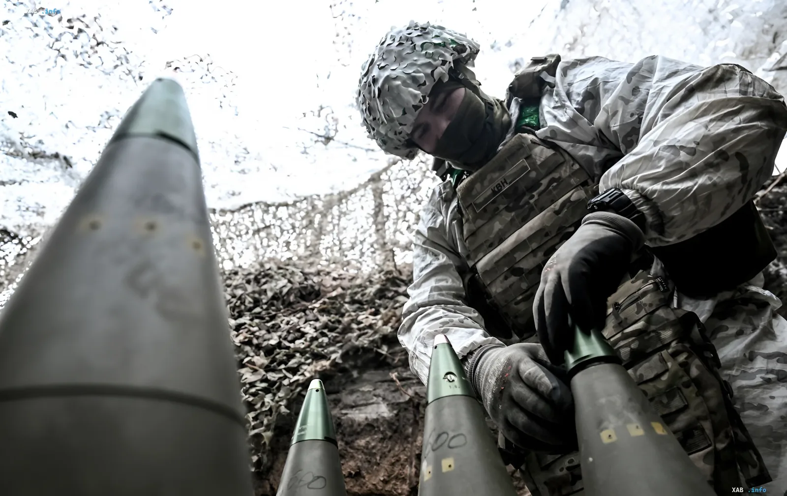Военнослужащий Сил обороны Украины в камуфляже готовит к применению дальнобойные 155-мм артиллерийские снаряды, иллюстрируя проблему дефицита боеприпасов