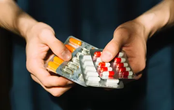 Hands holding blister packs of pills and capsules — medicines under the 'Affordable Medicines' program now delivered by drones in Ukraine