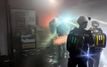 Firefighters in protective gear working inside a smoke-filled shopping center in Kryvyi Rih after a repeat missile strike