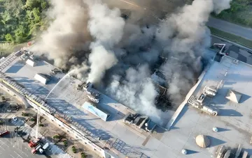 Aerial view of the fire after a strike on a shopping center in Kryvyi Rih: thick smoke over the damaged roof and firefighters at work