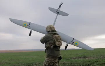 Украинский военный с беспилотным летательным аппаратом на фоне степи — инструмент СБС в борьбе с теневым флотом и энергообъектами РФ