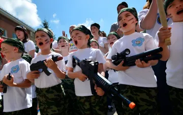 Young children in camouflage with toy weapons in occupied territory