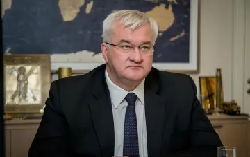 Swedish Foreign Minister Tobias Billström in a formal portrait with a world map in the background