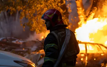 Firefighter in front of a burning car after the evening Russian missile strike on Mykolaiv Oblast