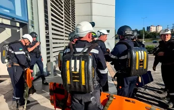 Rescuers in protective gear with breathing apparatus at the entrance of a shopping mall in Kryvyi Rih after strikes on the building, with orange stretchers nearby for evacuating the injured