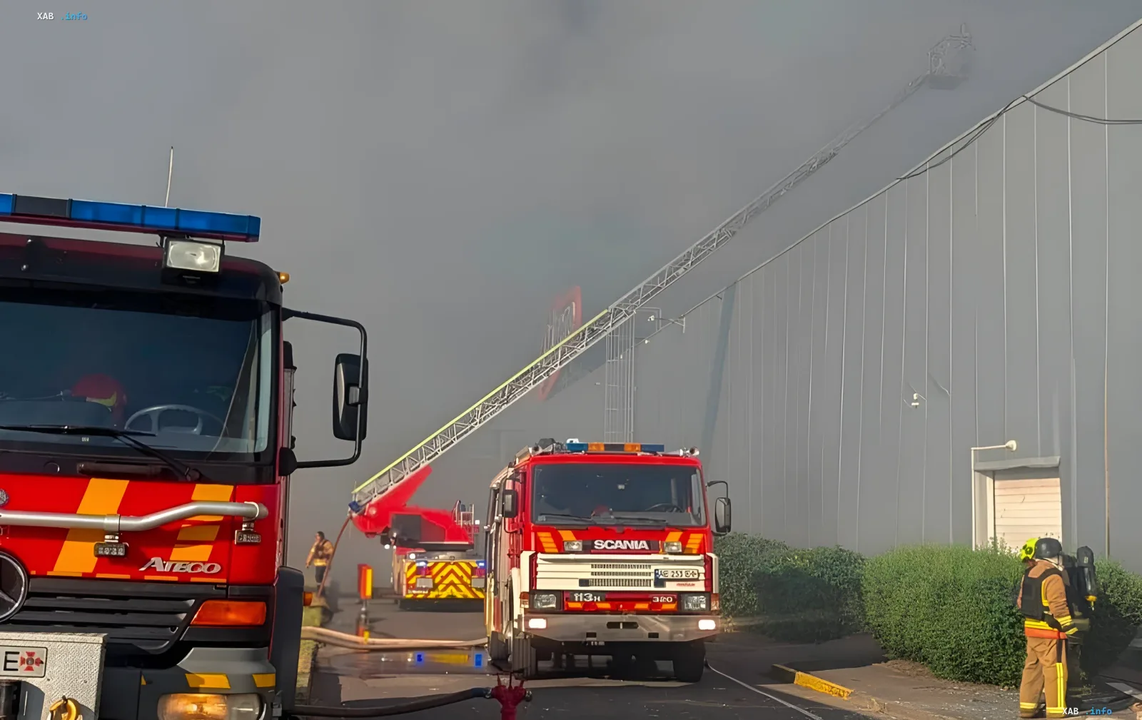 Fire trucks and an elevated platform ladder at a smoke-covered shopping center in Kryvyi Rih after a strike, firefighters working on the aftermath