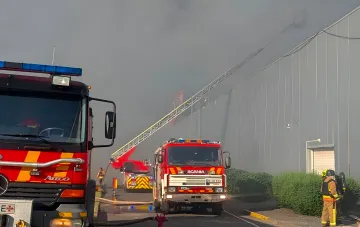 Fire trucks and an elevated platform ladder at a smoke-covered shopping center in Kryvyi Rih after a strike, firefighters working on the aftermath