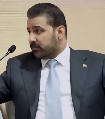 Iraqi Prime Minister at a microphone during a speech on budget shortfalls and the anti-corruption campaign