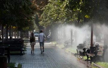 Прогулка в парке в жаркий день: система распыления воды охлаждает аллею во время аномальной жары в Украине