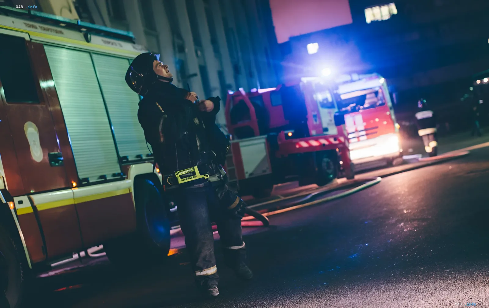 Firefighter in protective gear at the site of a drone strike on an Ozon logistics center at night