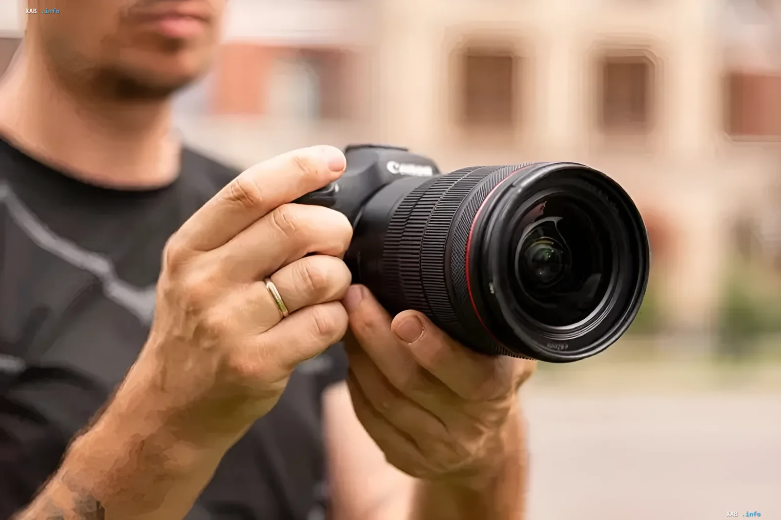 A photographer holding a professional Canon mirrorless camera with an L-series lens
