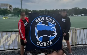 Фанаты одесского «Черноморца» из группировки New Kids Odessa держат баннер с логотипом на фоне футбольного поля после сенсационного вылета из Кубка Украины