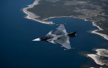 Swedish Saab JAS 39 Gripen fighter jet flying over the coastline — ready to defend Ukrainian airspace