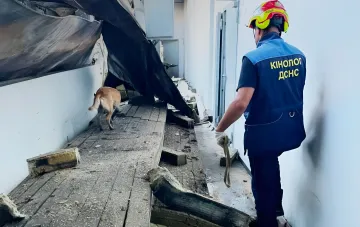 Кинолог ДСНС с служебной собакой ведёт поиск пропавших под завалами разрушенного торгового центра в Кривом Роге